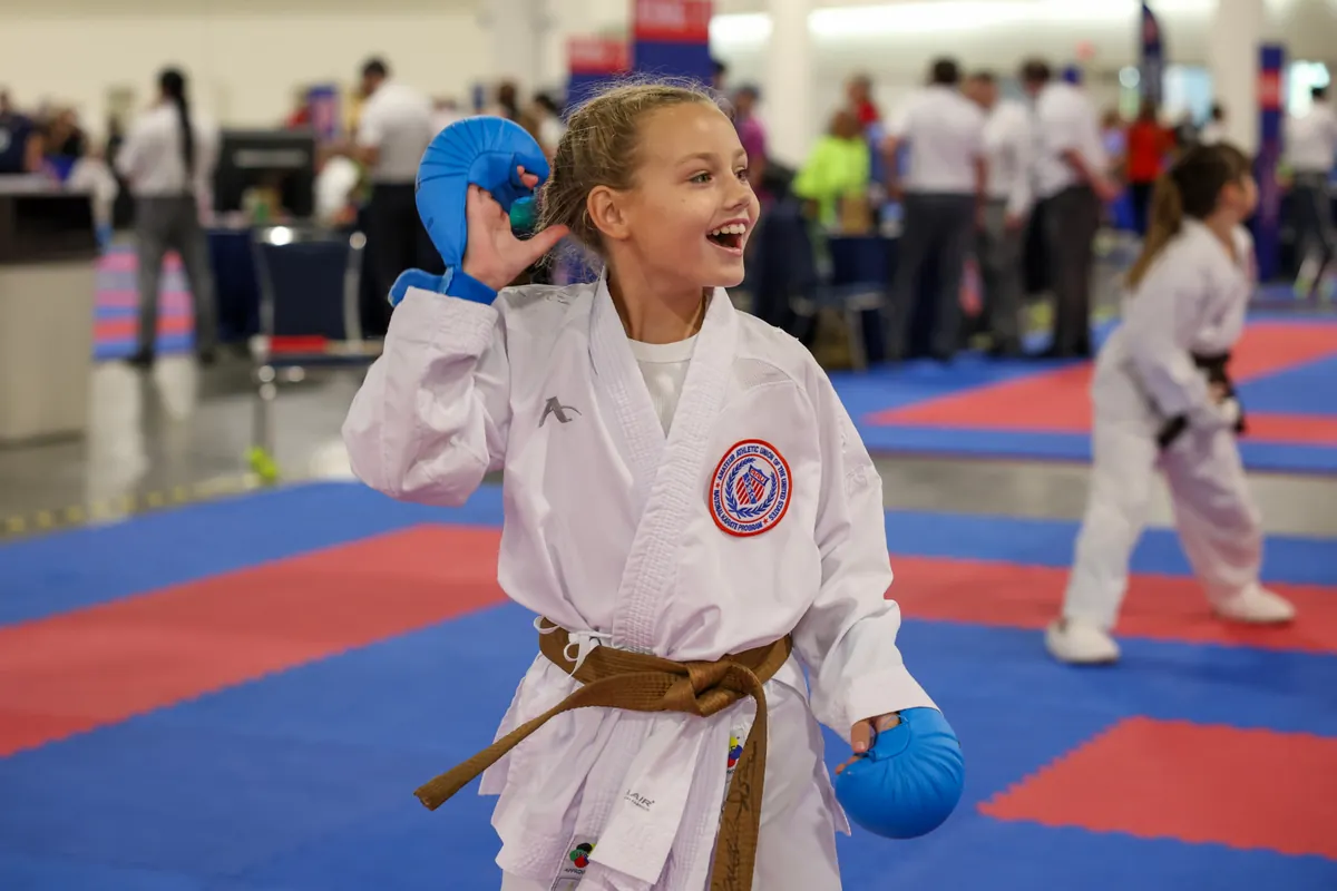 Student athlete Dominika Tsybina smiling on the tatami in karate sparring gloves